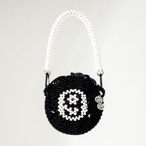 Black beaded handbag with white pattern on a white background