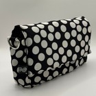 Black clutch bag with white polka dots on a light gray background