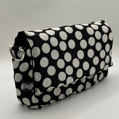 Black clutch bag with white polka dots on a light gray background