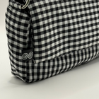 Black and white checkered pouch with a metal ring on a light gray background