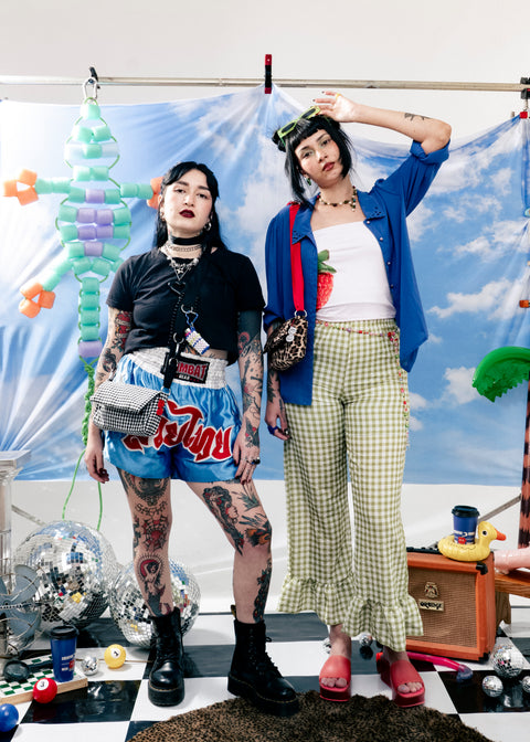 Two people posing in front of a colorful backdrop with a checkered floor.